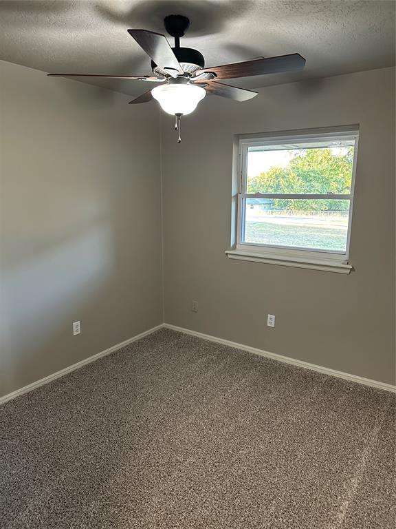 unfurnished room featuring ceiling fan, carpet, and a textured ceiling