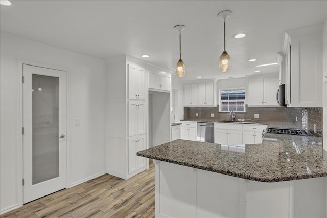 kitchen with white cabinets, hanging light fixtures, light hardwood / wood-style flooring, appliances with stainless steel finishes, and kitchen peninsula