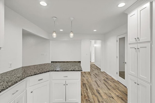 kitchen featuring pendant lighting, light hardwood / wood-style flooring, white cabinetry, and dark stone counters