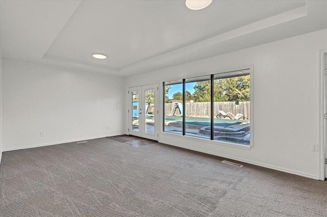 carpeted empty room with a tray ceiling