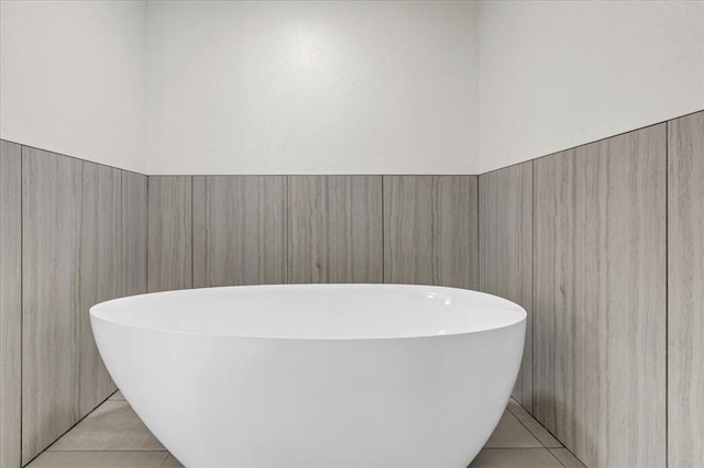 bathroom featuring tile patterned floors, a washtub, and tile walls