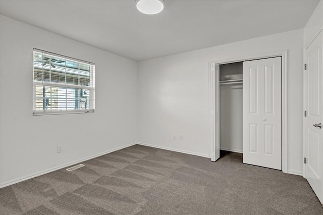 unfurnished bedroom featuring dark colored carpet and a closet