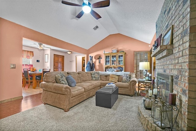 living room featuring a fireplace, carpet flooring, vaulted ceiling, and ceiling fan