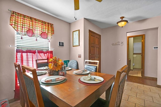 dining space featuring ceiling fan, light tile patterned floors, and a textured ceiling