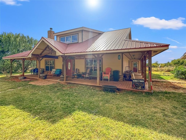 back of property featuring metal roof, a patio area, a yard, and a chimney