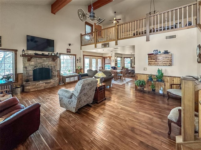 living area featuring a wainscoted wall, a fireplace, visible vents, wood finished floors, and beamed ceiling