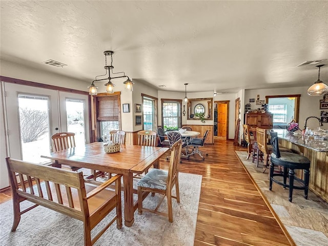 dining space featuring a textured ceiling, french doors, light wood-type flooring, and visible vents