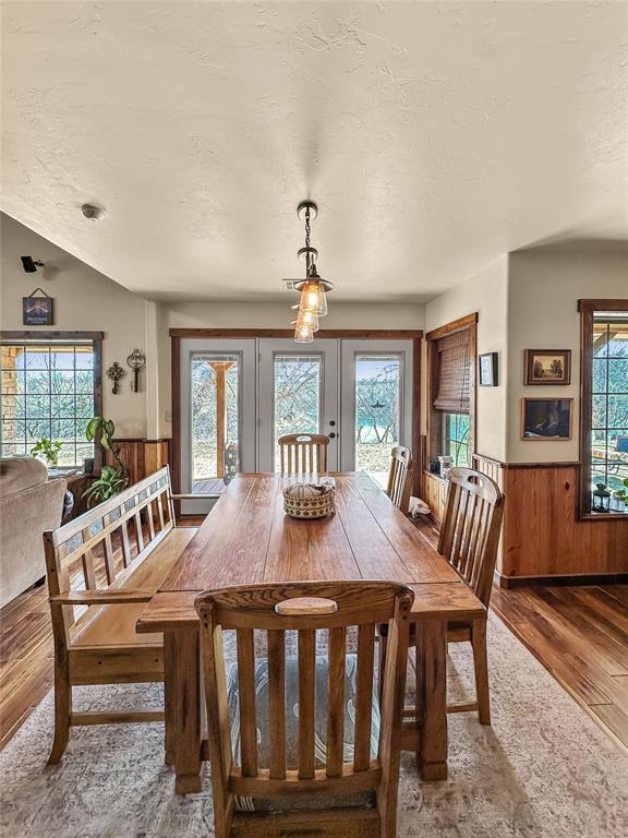 dining area featuring a wainscoted wall, wooden walls, a textured ceiling, and wood finished floors