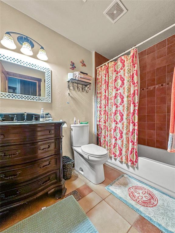 bathroom featuring visible vents, toilet, shower / bath combo, vanity, and tile patterned floors