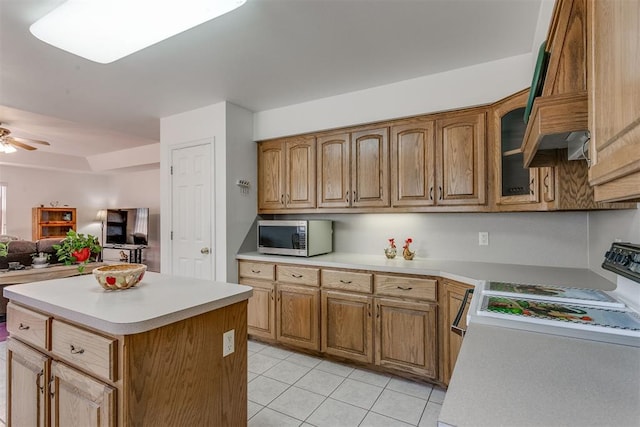 kitchen with ceiling fan, stove, light tile patterned floors, and a kitchen island