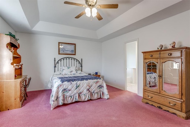 bedroom with carpet flooring, ceiling fan, a raised ceiling, and ensuite bath