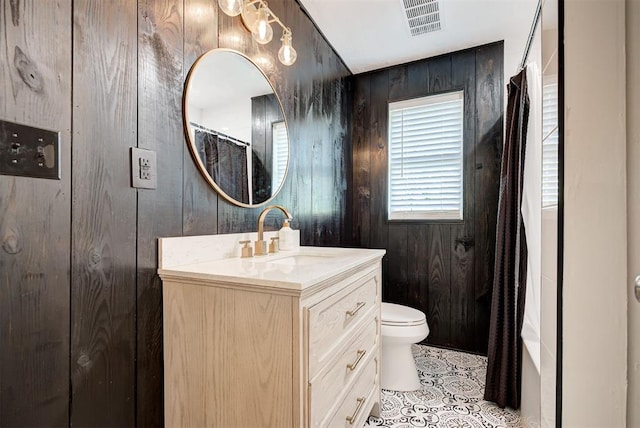 bathroom with tile patterned floors, vanity, wood walls, and toilet