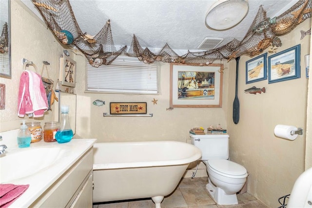 bathroom with a tub to relax in, tile patterned floors, a textured ceiling, vanity, and toilet