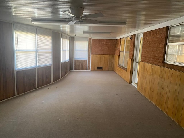 spare room featuring ceiling fan and wooden walls