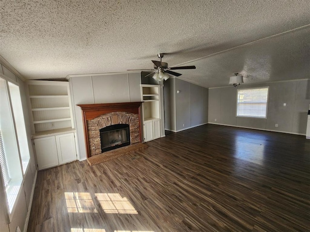 unfurnished living room featuring a textured ceiling, dark hardwood / wood-style floors, a brick fireplace, and ceiling fan