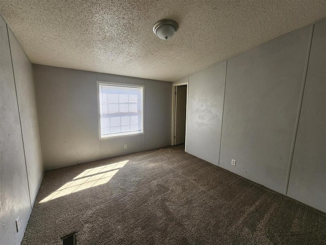 carpeted empty room with a textured ceiling