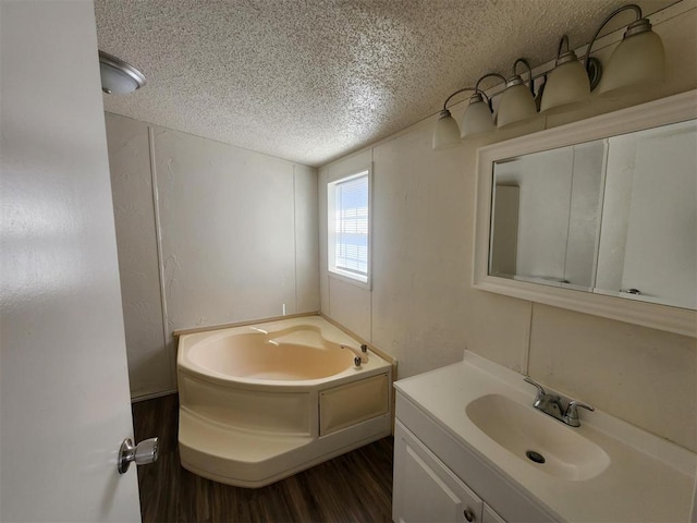 bathroom with vanity, a bath, a textured ceiling, and wood-type flooring