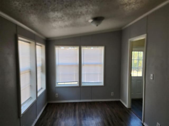 spare room with a textured ceiling, dark hardwood / wood-style floors, lofted ceiling, and crown molding