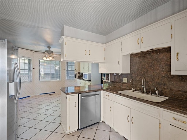 kitchen with white cabinets, sink, light tile patterned floors, appliances with stainless steel finishes, and kitchen peninsula