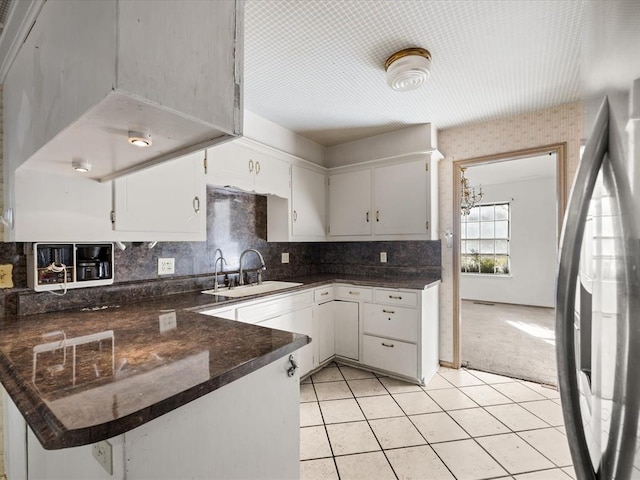 kitchen featuring light carpet, kitchen peninsula, stainless steel fridge, sink, and white cabinets