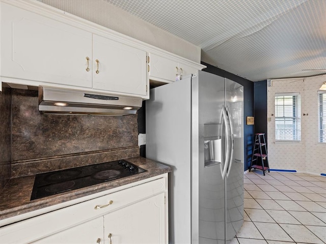 kitchen with stainless steel fridge, black electric stovetop, extractor fan, light tile patterned floors, and white cabinets