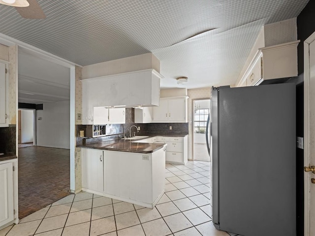 kitchen with stainless steel fridge, sink, white cabinets, and ceiling fan