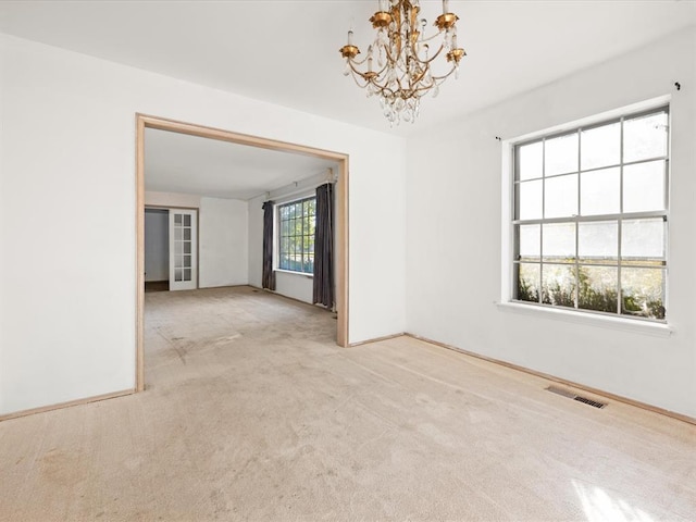 carpeted spare room featuring a chandelier