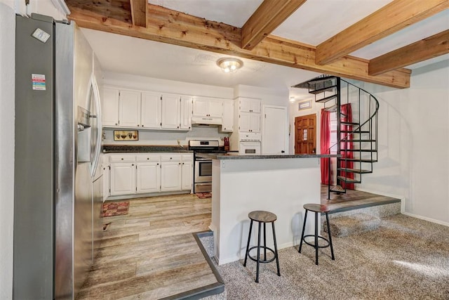 kitchen with appliances with stainless steel finishes, a kitchen breakfast bar, light hardwood / wood-style flooring, beamed ceiling, and white cabinetry