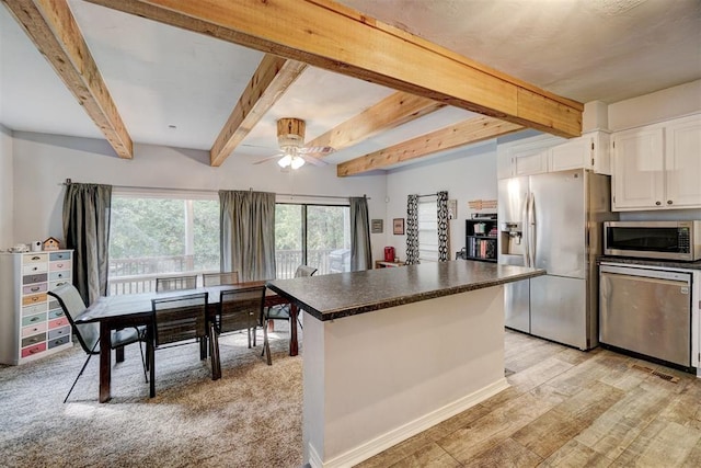 kitchen with beam ceiling, white cabinetry, a center island, stainless steel appliances, and light hardwood / wood-style flooring