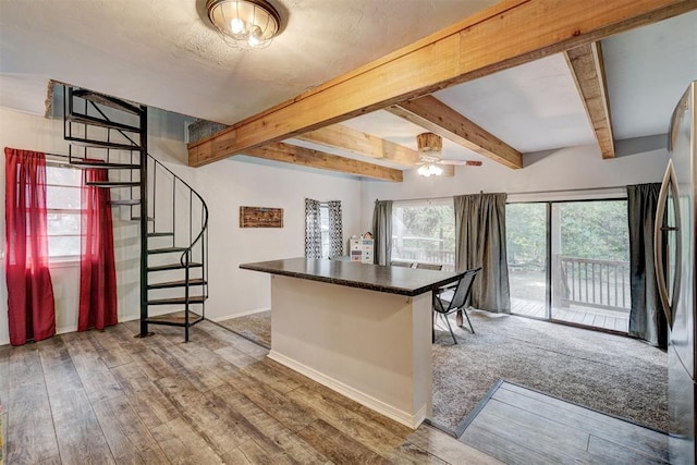 kitchen with hardwood / wood-style floors, a kitchen breakfast bar, ceiling fan, beamed ceiling, and stainless steel refrigerator