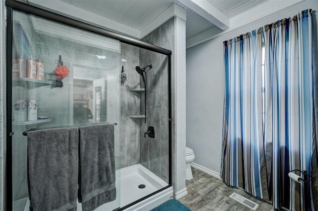 bathroom featuring beamed ceiling, wood-type flooring, a shower with shower door, and toilet