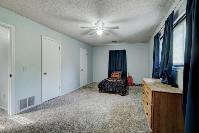 carpeted bedroom featuring ceiling fan and a textured ceiling