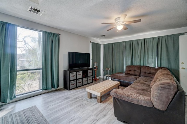 living room with ceiling fan, light hardwood / wood-style floors, and a textured ceiling