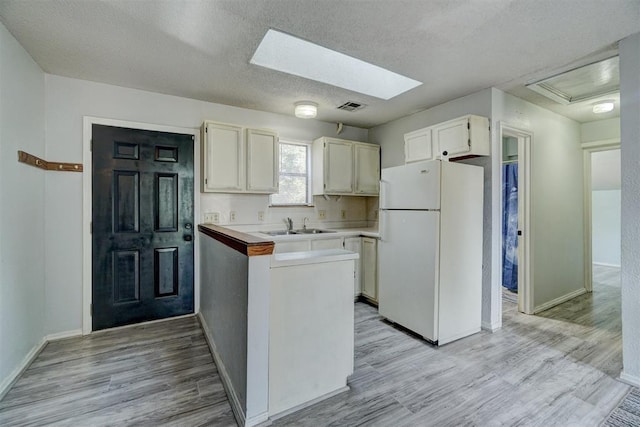 kitchen featuring a textured ceiling, white fridge, light hardwood / wood-style floors, and sink