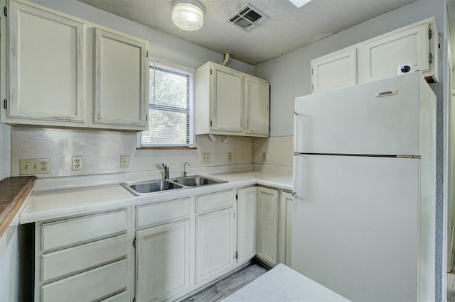 kitchen featuring sink, a textured ceiling, and white refrigerator