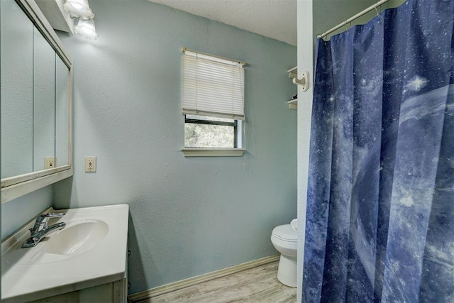 bathroom with vanity, a textured ceiling, wood-type flooring, toilet, and curtained shower