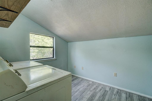 clothes washing area with light wood-type flooring, a textured ceiling, and washing machine and dryer