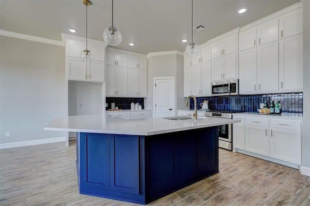 kitchen featuring appliances with stainless steel finishes, sink, pendant lighting, and an island with sink