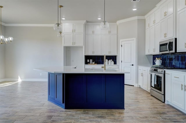 kitchen featuring appliances with stainless steel finishes, tasteful backsplash, decorative light fixtures, a center island with sink, and white cabinetry