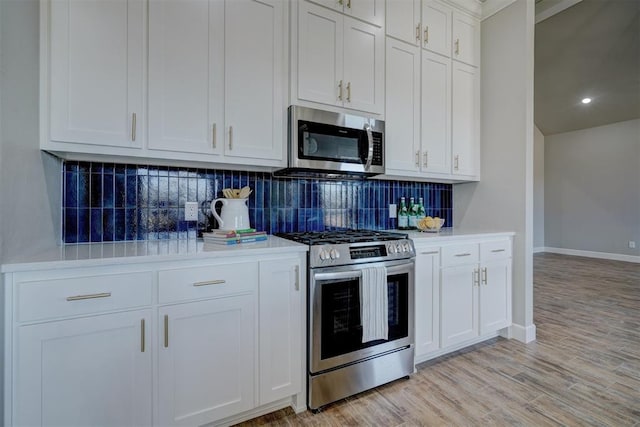 kitchen featuring decorative backsplash, white cabinetry, stainless steel appliances, and light wood-type flooring