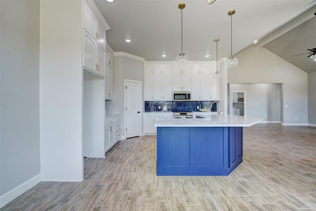 kitchen featuring light wood-type flooring, stainless steel appliances, a large island, white cabinets, and lofted ceiling