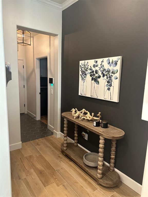 corridor featuring crown molding, hardwood / wood-style floors, and an inviting chandelier