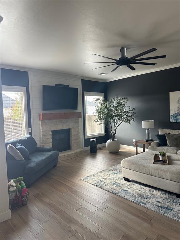 living room with hardwood / wood-style flooring, a brick fireplace, ceiling fan, and ornamental molding