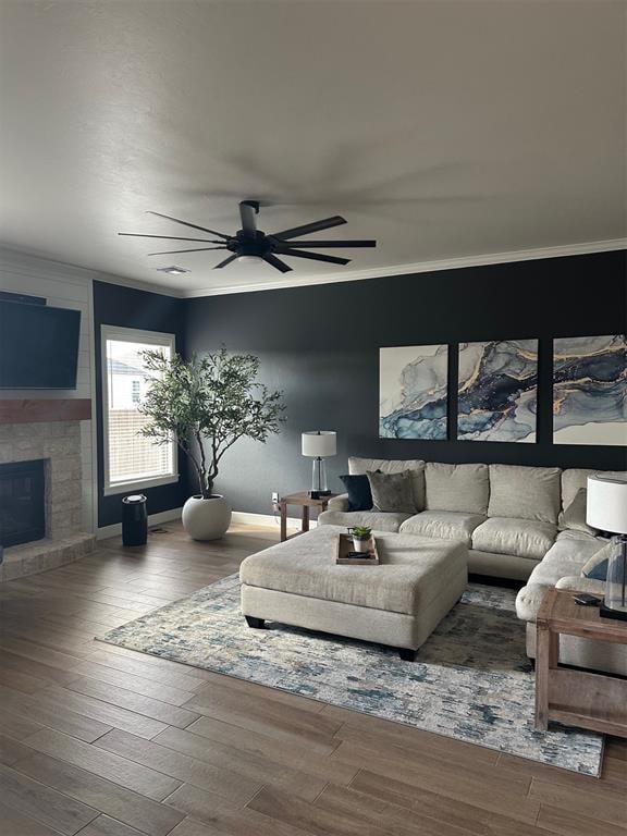 living room with a fireplace, ceiling fan, wood-type flooring, and ornamental molding