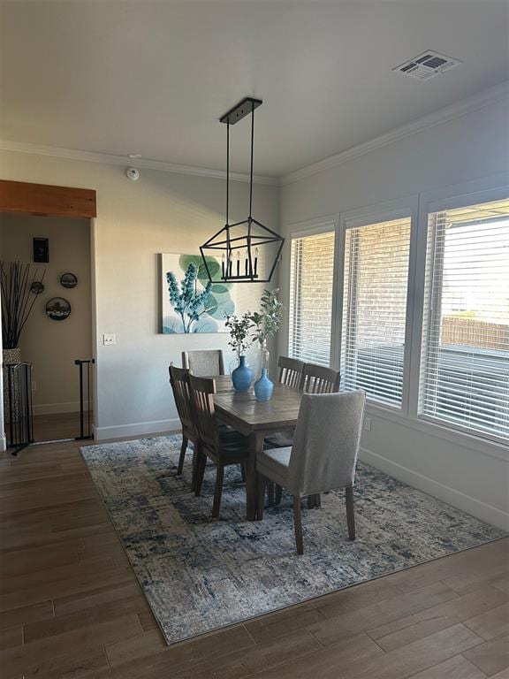 dining area with a chandelier, crown molding, and dark wood-type flooring