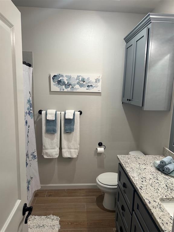 bathroom featuring curtained shower, toilet, vanity, and hardwood / wood-style flooring