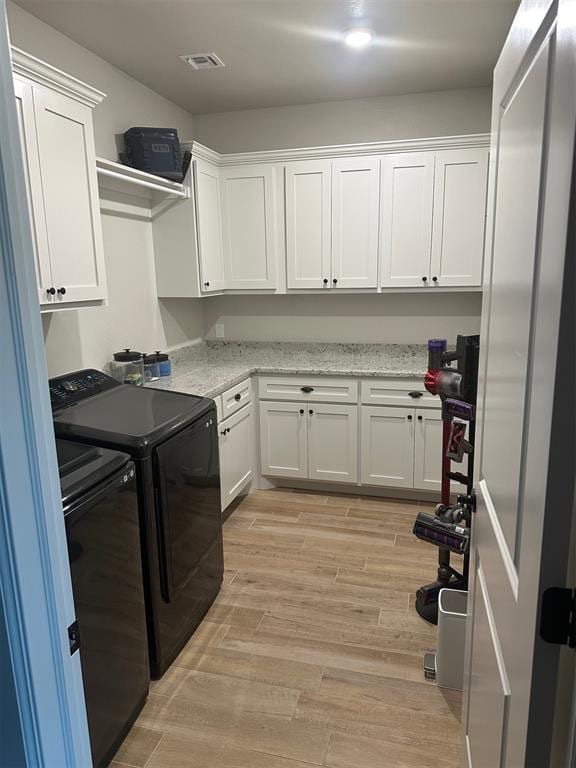 laundry area featuring washer and dryer, light hardwood / wood-style floors, and cabinets