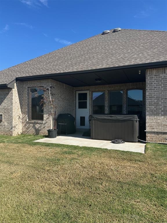 rear view of house featuring a yard, a patio, and a hot tub