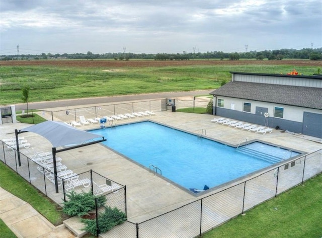 view of swimming pool with a patio area and a rural view