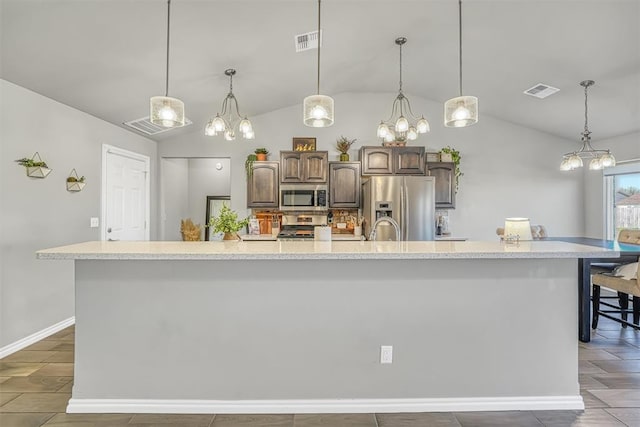 kitchen with dark brown cabinetry, a large island with sink, decorative light fixtures, lofted ceiling, and appliances with stainless steel finishes